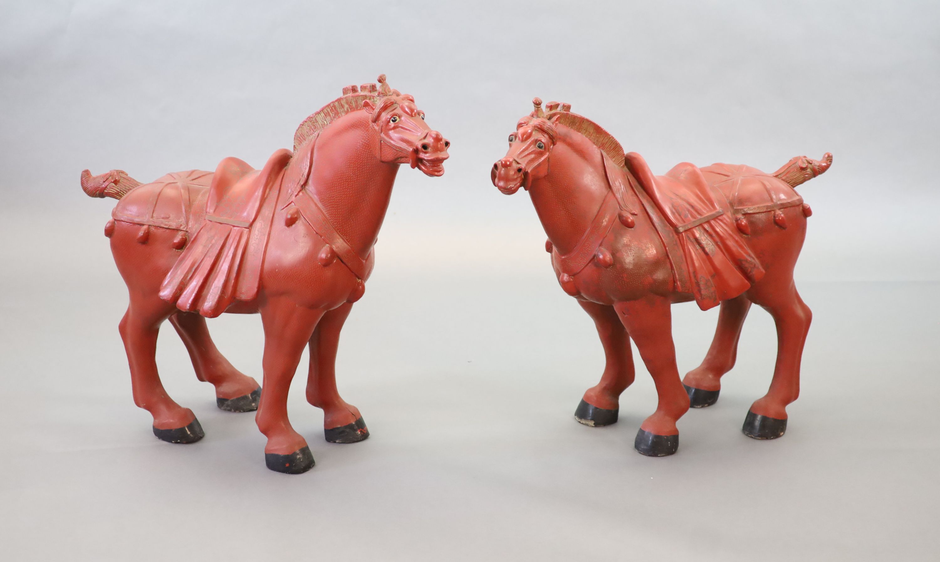 A pair of Chinese cinnabar lacquered horses with plinth stands
